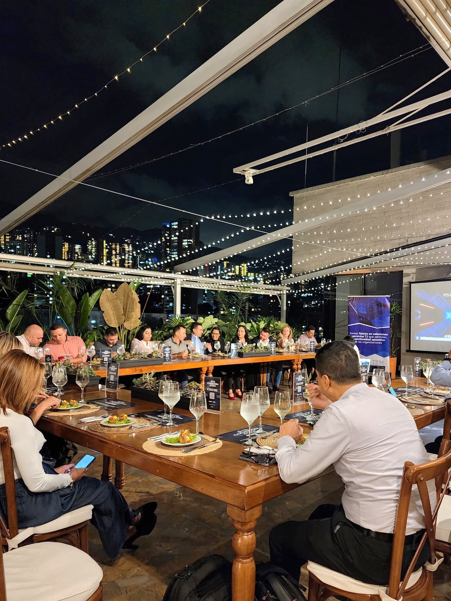 Cena empresarial en terraza con vista nocturna a Medellín, montaje de evento corporativo